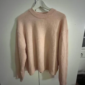 Rosa stickad tröja - Mysig rosa stickad tröja med rund hals och långa ärmar. Perfekt för kyliga dagar och ger en stilren look. Tröjan har en mjuk och fluffig textur som känns skön mot huden.