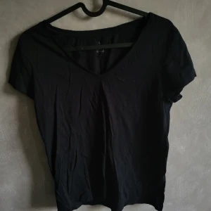 Svart t-shirt från Our Best Basics - Säljer en enkel och stilren svart t-shirt från Our Best Basics. T-shirten har en v-ringad hals och korta ärmar, perfekt för en avslappnad look. Tillverkad i bomull för en skön känsla.