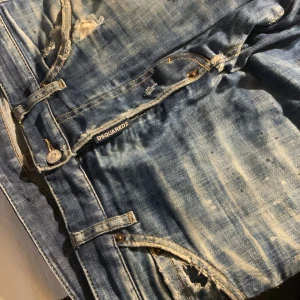 Blå jeans från Dsquared2 - Snygga blå jeans från Dsquared2 med slitna detaljer och en cool vintage-look. Jeansen har en klassisk femficksdesign och en läderpatch med logotyp på baksidan. Perfekta för en avslappnad stil.