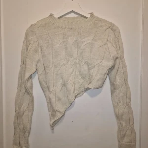 Stickad tröja med byxor  - Säljer ett mysig stickad set i beige/cremé färg. Tröjan har ett kabelstickat asymmetrisk mönster. Garderobsrensning så kika gärna på övriga auktioner. Tröjan har stl 36 och byxorna stl 38