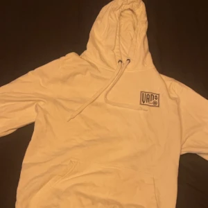 Vit hoodie från Vans - Säljer en stilren vit hoodie från Vans med klassisk logga på bröstet och stort tryck på ryggen. Nästan aldrig använd. Nypris 540