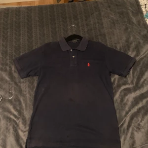 Mörkblå pikétröja från Ralph Lauren - Säljer min piké från Ralph lauren då den blivit för liten. Den är i storlek m och passar den som bär storlek m-s. Tyvärr har tröjan fått sig fläckar, dock inget som märks överdrivet mycket. Piken har tecken på användning t.ex att den börjat bli urtvättad. Undrar du nått är det bara att höra av dig mvh.