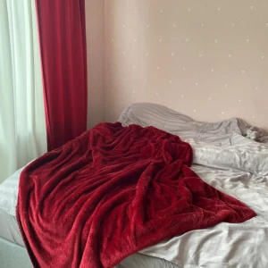 Mjuk röd filt - Säljer en supermjuk och fluffig röd filt som är perfekt för mysiga kvällar. Filten har en djup röd färg och ser ut att vara gjord av ett plyschmaterial.