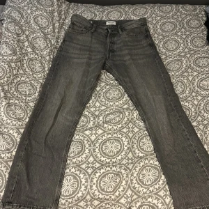 Grå jeans från Jack & Jones - Säljer ett par grå jeans från Jack & Jones. De har en klassisk femficksdesign och är tillverkade i slitstarkt denim. Perfekta för en avslappnad stil.