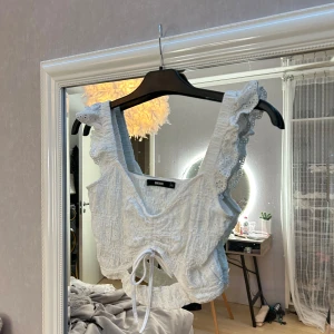 Vit spetslinne från Bik Bok -  Söt vitt spets linne från Bik Bok med knytning framtill och volangdetaljer på axelbanden. Perfekt till sommaren! Endast använd en gång