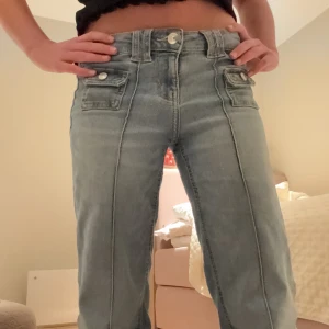 Bootcut jeans  - Snygga blå jeans med unika fickdetaljer och knappstängning. Byxorna har en bootcut-stil 