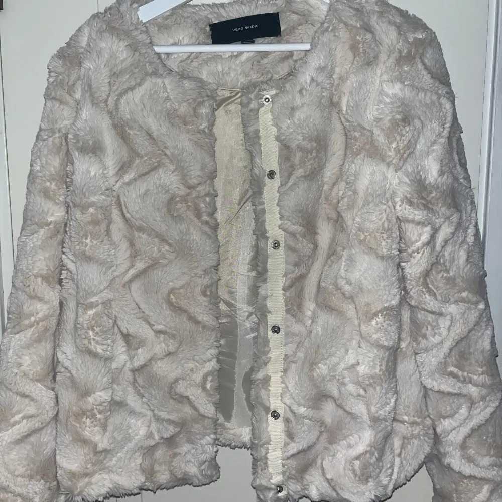 Säljer en fluffig beige/vit pälsjacka från Vero Moda. Jackan har knappar. Den ser smutsig ut på grund av ljuset men är helt ren o fin. . Takit.