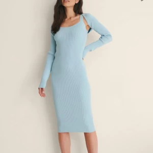 Ljusblå ribbad klänning - Trendig ljusblå klänning med ribbad struktur och offshoulder-design. Klänningen har långa ärmar och en tight passform som framhäver figuren. Perfekt för en stilren look. Köpt för 649kr!!