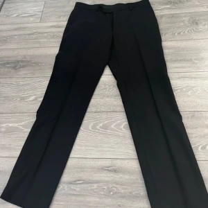 Kostymbyxa - Eleganta svarta kostymbyxor i Super 100's ull. Perfekta för formella tillfällen med en klassisk passform. Midjemått W34 och längd L32 (herrstorlek). Dessa är aldrig använda, ny pris : 800kr🥀