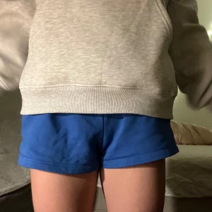 Blå shorts med snörning - Säljer ett par blå mjukis shorts! Perfekta till att gymma/träna eller för en bekväm look. De är super bekväma och kan vikas ner vid midjan. Vet ej storleken men passar mig som är S