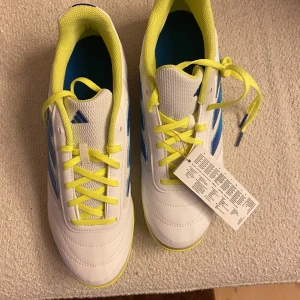 Vita Adidas inomhus  fotbollsskor - Snygga vita Adidas fotbollsskor med gula och blå detaljer.  för inomhusfotboll. ej använda.