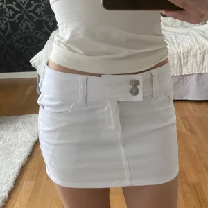 Minikjol - Vit lågmidjad minikjol med två dekorativa knappar framtill🤍