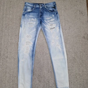 Blå slitna jeans från Replay - Snygga blå jeans från Replay med slitna detaljer och en modern look. Använd få gånger ganska ny sick jeansen är ganska tajta 