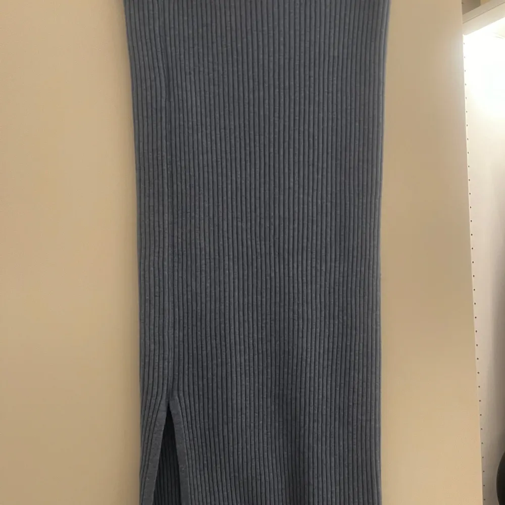 Snygg blå ribbad midikjol från NA-KD i storlek M. Kjolen har en stilren design med en slits framtill som ger en modern touch. Perfekt för både vardag och speciella tillfällen.. Hameet.
