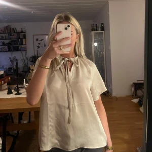 Beige blus med knytband - En beige blus med knytband vid halsen. Använts 2 gånger