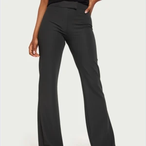 Mörkgrå midwaist kostymbyxor - Snygga mörkgrå kostymbyxor med en elegant och stilren design. Byxorna har en mellanhög midja och en rak passform som ger en klassisk look. Perfekta för en chic och sofistikerad stil.