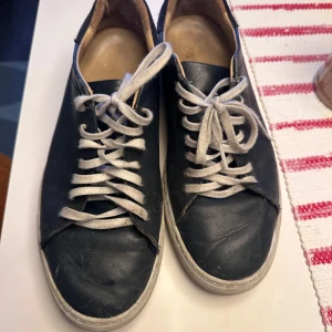 Axel arigato skor navy - Snygga navy sneakers från Axel Arigato med vit sula och snörning. Perfekta för en stilren look.