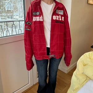 Röd racingjacka ferrari - Cool röd racingjacka med vita tryck och broderade detaljer. Jackan har en oversized passform och långa ärmar. Perfekt för dig som vill sticka ut med en sportig stil.