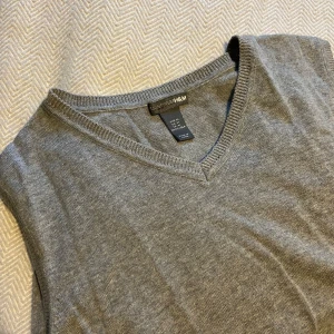 Grå V-ringad tröja från H&M - Grå V-ringad tröja från H&M. Perfekt för lager-på-lager eller som den är. Tröjan är i ett mjukt material och har en klassisk passform.