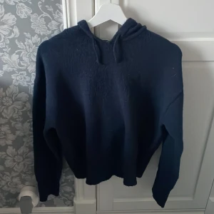 Mörkblå hoodie från Gina Tricot - Säljer en mysig mörkblå hoodie från Gina Tricot. Tröjan har en luva och långa ärmar, perfekt för kyligare dagar. Den är tillverkad i ett mjukt material som känns skönt mot huden.