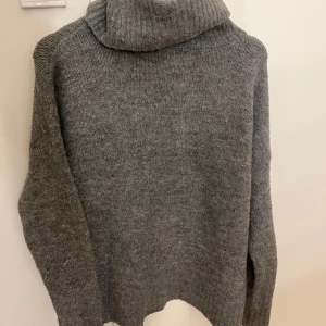Grå stickad polotröja - Mysig grå stickad polotröja med hög krage. Perfekt för kyliga dagar med sin varma och bekväma design. Tröjan har långa ärmar och en avslappnad passform. pris kan diskuteras vid snabbt köp