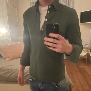 John Henric tröja - Mörkgrön ”pop over” skjorta från John Henric. Mycket bra skick. Jag på bilden är ca 183cm och väger ca 73kg, anser att den är lite för liten för mig.