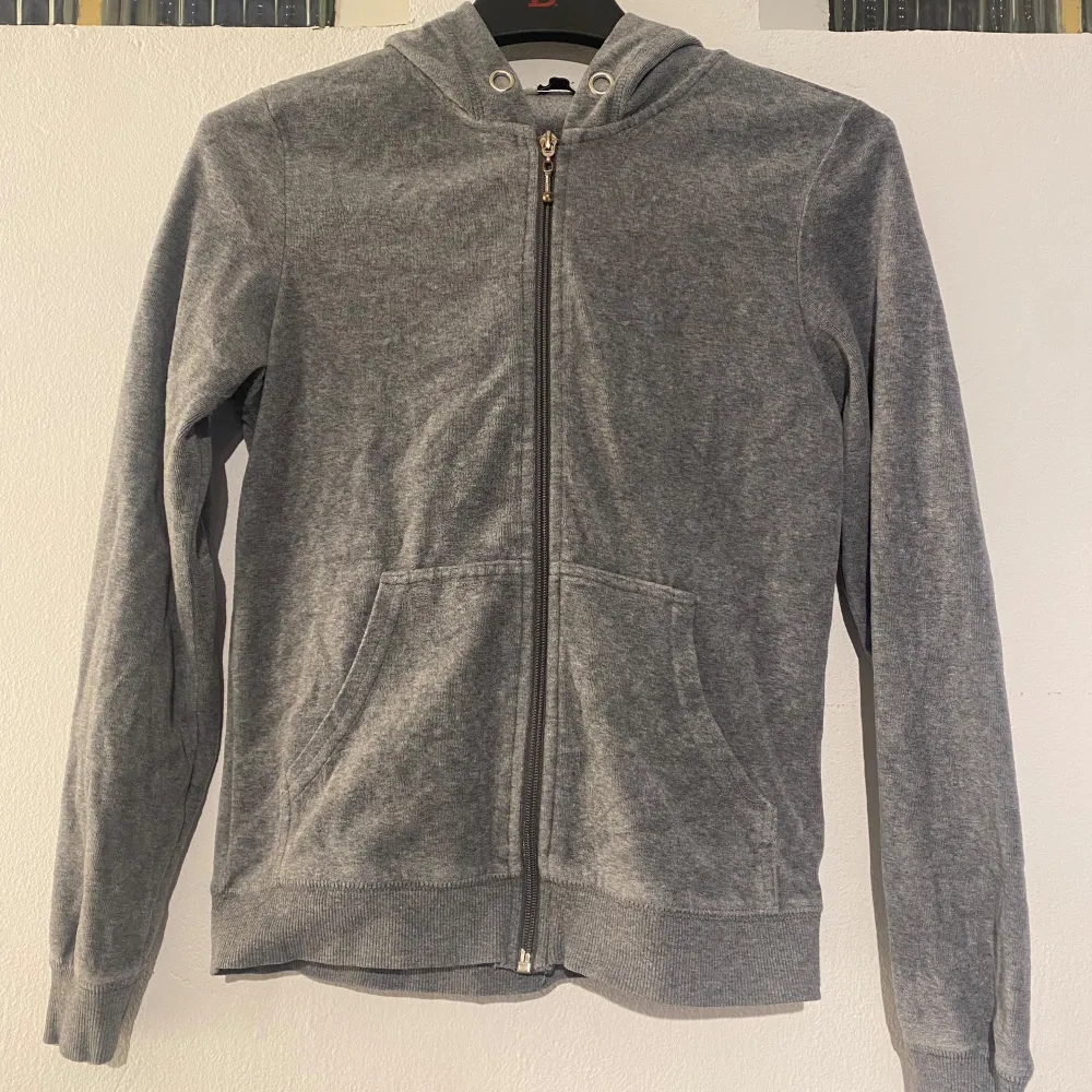 Säljer en stilren grå hoodie med dragkedja framtill. Tröjan har långa ärmar och en praktisk huva. Perfekt för en avslappnad look. Spännet på dragkedjan har tappat lite färg. . Neuletakit & Villapaidat.