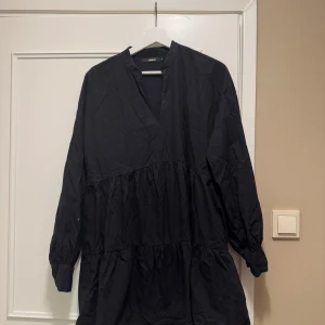 Svart klänning från Bik Bok - Snygg svart klänning från Bik Bok i storlek S. Klänningen har en v-ringad design med långa ärmar och volangdetaljer som ger en fin siluett. Är en aning luddig för att den lekar bredvid en fluffig kofta. 