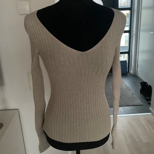 Beige ribbad tröja - Snygg beige ribbad tröja med v-ringad hals och långärmade ärmar. Perfekt för en stilren look.