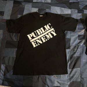 Svart t-shirt från Supreme x Undercover - Cool svart t-shirt från Supreme i samarbete med Undercover. Framsidan har texten 'Public Enemy' i vitt, medan baksidan har ett grafiskt tryck med texten 'Blow Your Mind'. Tillverkad i 100% bomull. Dm vid frågor:)