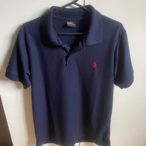 Raulph Lauren Piké mörkblå - Tja säljer denna mörkblåa pikén från Raulph Lauren då den blivit för liten och används inte. Användes typ 3-4 gånger och de var bara utomlands. Sjukt snygg nu till sommaren!