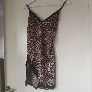 Leopardmönstrad klänning med spetsdetaljer - Säljer en superfin leopardmönstrad klänning/negilge med svarta spetsdetaljer. Den är ärmlös och har smala axelband. Materialet känns mjukt och lyxigt mot huden.