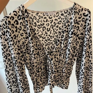 Leopardmönstrad blus från Zara - Säljer en superfin leopardmönstrad blus från Zara. Den har en v-ringad design med knytning framtill och långa ärmar. Perfekt för både vardag och fest! 🐆