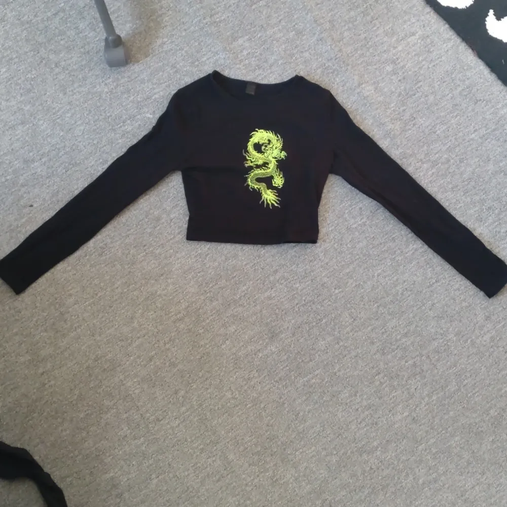 Cropped långärmad emo tröja med en neongrön drake på. Tröjan är gjord i bommul och använd några fåtal gånger. Färgen syns inte så bra på bild (mest sista bilden) men är starkt neongrön i verkligheten. . Yläosat.