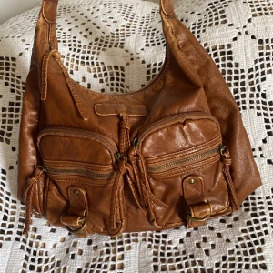 Väska - Mellanstor väska i ljusbrun/rostig färg! Bra skick⭐️ Den har dragkedja och flera små fack både på insidan och utsidan! Kan fixa mått om så önskas!!