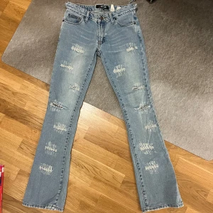 Lågmidjade vintage ripped jeans - Lågmidjade acoola jeans. Utsvängda i modellen. Jättesnygga små hål som sitter lite överallt. Aldrig använda då de har varit försmå (har försöka göra de större genom att klippa på sidorna, se sista bilden). Det står ingen storlek men skulle gissa xs/s