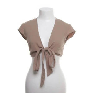 Beige Tie front Top - • Normal passform • Upplevs som storlek 36 • Sparsamt använd • Bild 4 visar färgen bäst • Relativt tunt och mjukt tyg