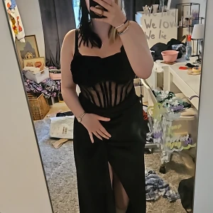 Svart klänning med slits - Säljer en elegant svart klänning med en djärv slits. Klänningen är ärmlös och har en tight passform som framhäver figuren. Perfekt för festliga tillfällen! tillhörande genomskynliga justerbara band. jag har 80 C i byst