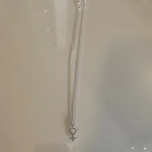 halsband  - Säljer ett stilrent silverhalsband från Ur&Penn med en hängande kvinnosymbol. Halsbandet har en enkel kedja och symbolen är dekorerad med små glittrande stenar. 
