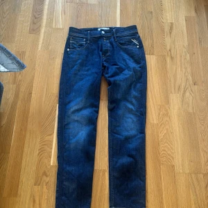 Mörkblå jeans från Replay - Säljer ett par snygga mörkblå jeans från Replay, modell Anbass. De är i slim fit och har en klassisk femficksdesign med dragkedja och knapp. Jeansen är i bra skick och perfekta för både vardag och fest. Passa på att fynda dessa stiliga jeans! aldrig andvänt dom