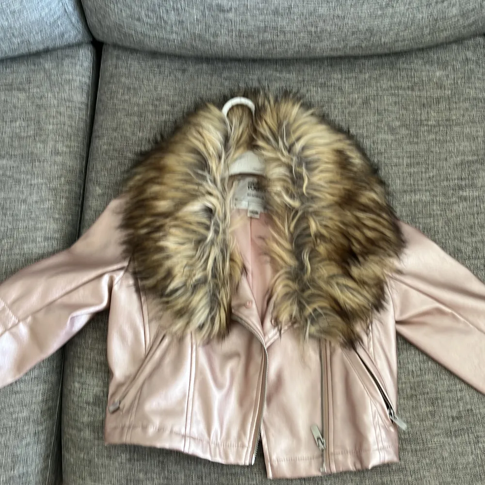 Säljer en superfin rosa skinnjacka från Mywear Young. Den har en fluffig fuskpäls runt kragen som ger en lyxig känsla. Jackan har dragkedjor framtill och på fickorna, vilket ger den en cool look. Perfekt för höst och vår!. Jackor.