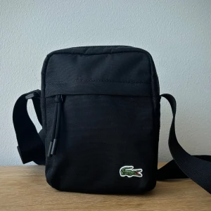 Axelremsväska från Lacoste  - Snygg väska i nyskick. Ordinarie pris 900kr 