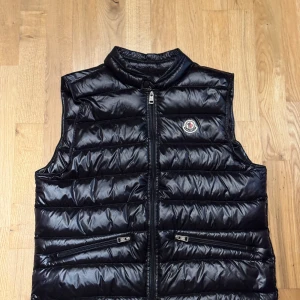 Svart dunväst från Moncler - Snygg moncler-gui väst i top skick, någon enstaka lös tråd kan förekomma men annars top skick. Västen är i storlek 3 men passar som en medium i vanliga storlekar. Kvitto kan jag kanske leta upp om jag skrollar i mejlen tilräckligt långt. Ställ gärna frågor, mvh Oscar. 