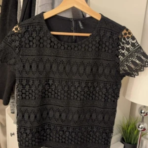 Svart spetsblus från Stradivarius - Snygg svart spetsblus från Stradivarius med korta ärmar och ett vackert spetsmönster. Storleken är L på tröja men passar mig perfekt som har storlek S