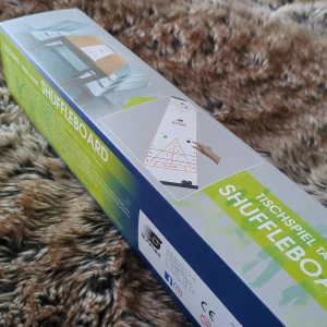 Shuffleboard spelset - Säljer ett shuffleboard spelset som är perfekt för bordsspel hemma. Setet innehåller en spelmatta och spelpjäser i gult och svart. Lätt att rulla ihop och förvara i den medföljande lådan. Perfekt för roliga spelkvällar med vänner och familj!