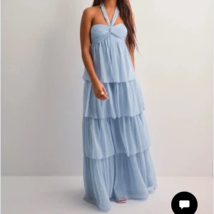 Ljusblå långklänning med halterneck - Elegante klänning från Nelly, har endast testat den hemma 1 gång men passade tyvärr inte och glömde skicka tbx så säljer den här nu, storlek S och är bra i längden för mig som är 175cm lång, man kan även ändra hur man vill bandet runt halsen ska sitta.
