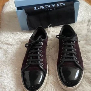 Svarta och vinröda sneakers från Lanvin - Snygga sneakers från Lanvin i svart och vinrött med glansig tå och snörning. Perfekta för en stilren look.
