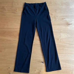 Svarta kostymbyxor - Snygga svarta kostymbyxor från Vero Moda med en klassisk design. Byxorna har en rak passform och är perfekta för en stilren look. 