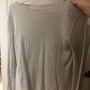 Beige långärmad topp från YAYA - Säljer en stilren beige långärmad topp från YAYA. Toppen har en texturerad yta och en rund halsringning. Perfekt för en enkel och elegant look.