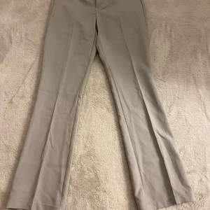 Grå kostymbyxor från BikBok - Snygga grå kostymbyxor från BikBok i storlek 38. Byxorna har en klassisk rak passform med diskreta fickor baktill. Perfekta för en stilren look.